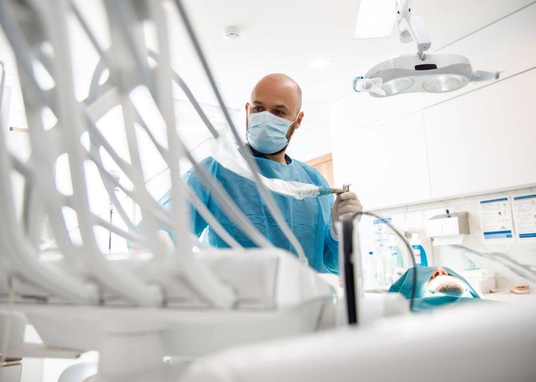 Odontologas su kauke ruo&scaron;iasi procedūrai odontologijos kabinete.